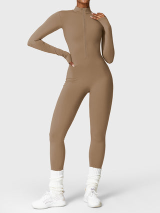 Fleece-lined beige long-sleeve jumpsuit with half-zip collar, styled for comfort and warmth, worn with white sneakers.